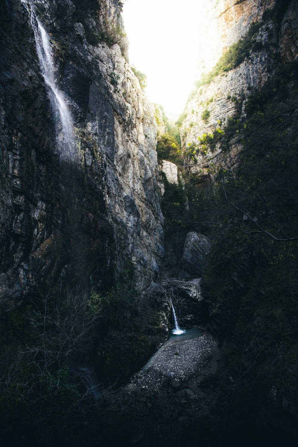 person in black jacket standing on rock near waterfalls during daytime