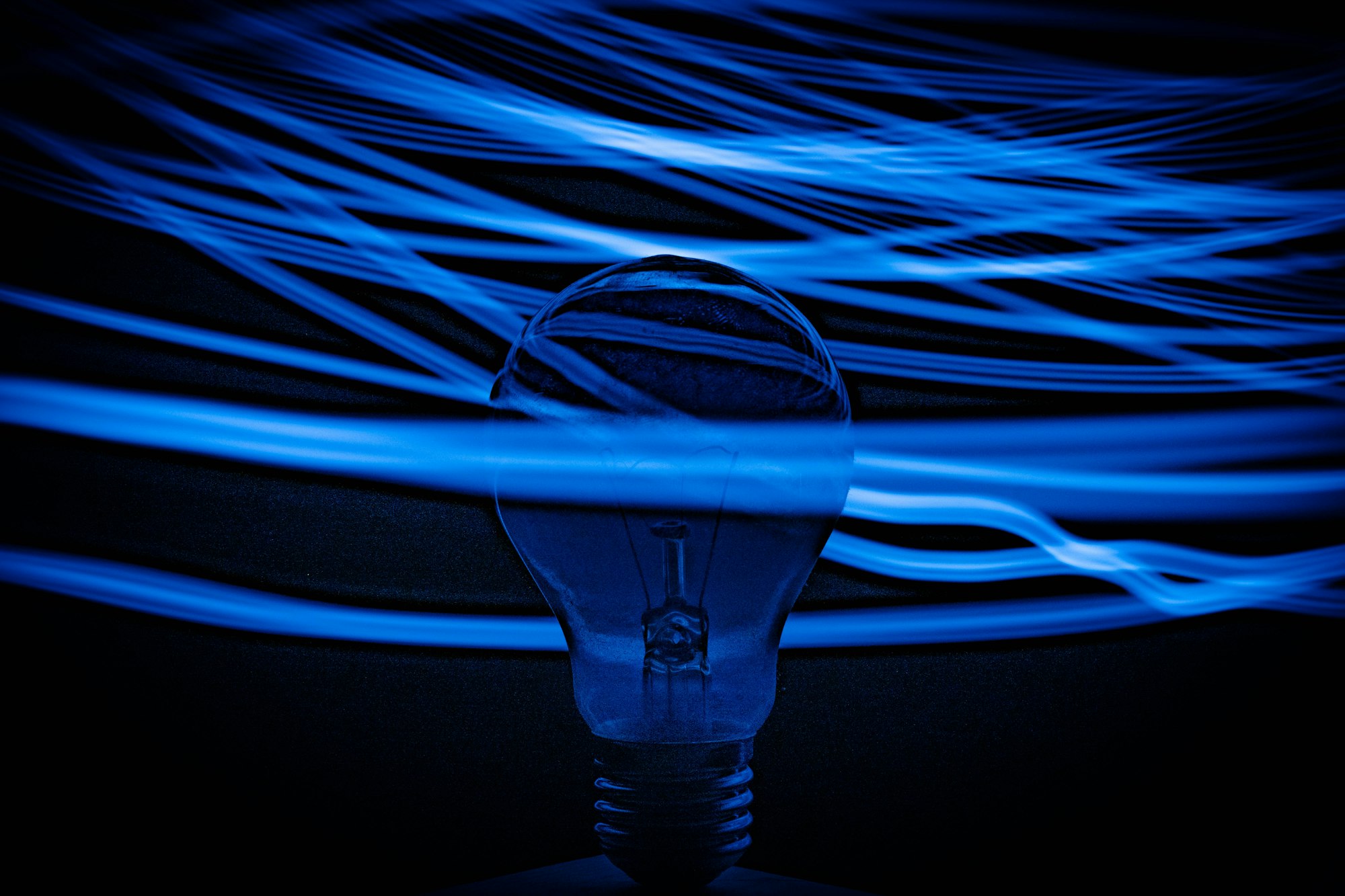 an incandescent light bulb surrounded by blue lines of light