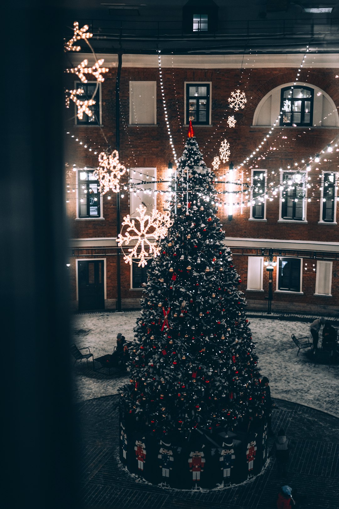 christmas tree with string lights in front of brown concrete building