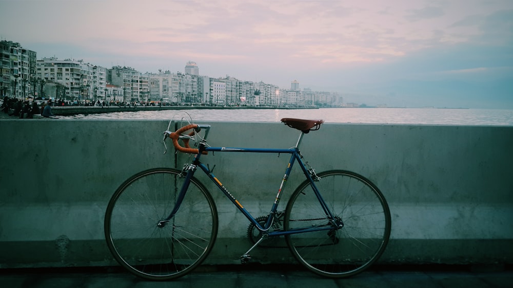 una bicicleta apoyada contra una pared cerca de un cuerpo de agua