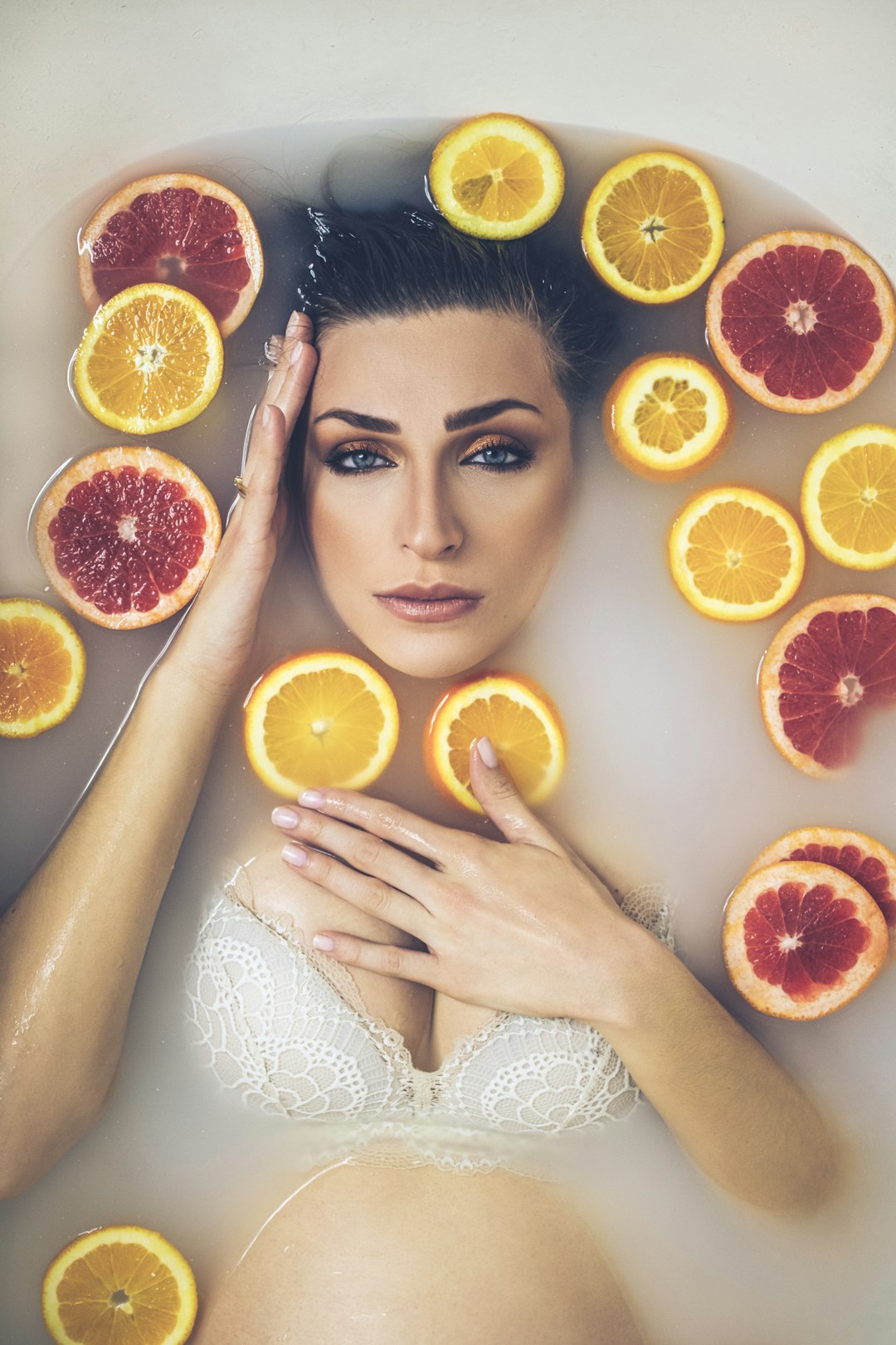woman in white tank top holding sliced orange fruit