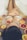 A pregnant woman is partially submerged in a bathtub filled with milky water, surrounded by slices of citrus fruits like oranges and grapefruits. She is wearing white lace clothing and resting her hands on her belly, creating a serene and intimate atmosphere.