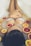 A pregnant woman is partially submerged in a bathtub filled with milky water, surrounded by slices of citrus fruits like oranges and grapefruits. She is wearing white lace clothing and resting her hands on her belly, creating a serene and intimate atmosphere.