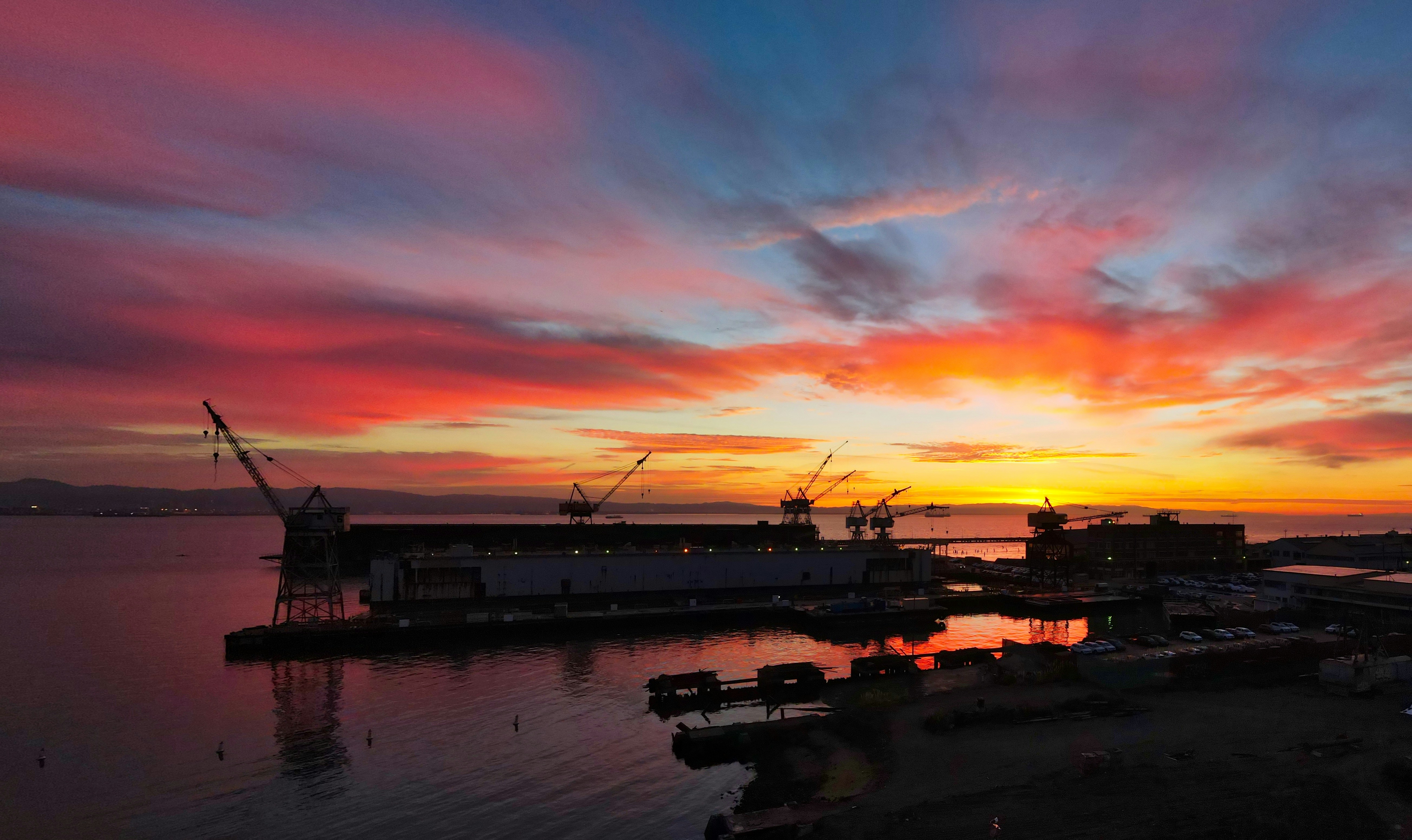 a sunset over a harbor with a boat in the water