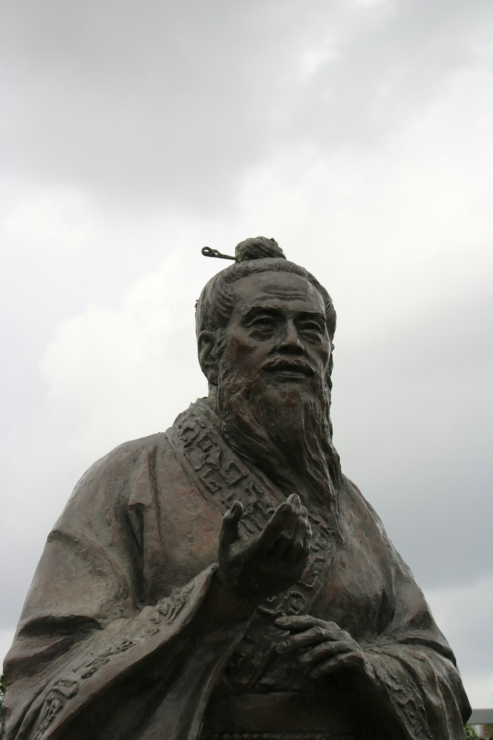 homem na estátua do chapéu sob nuvens brancas durante o dia