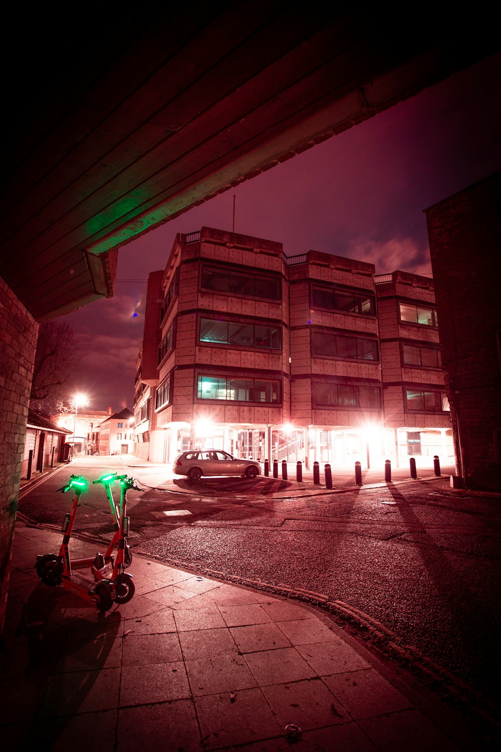 white and pink bicycle parked beside brown concrete building during night time