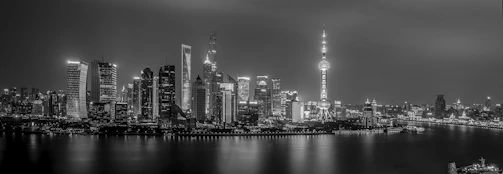 Panoramic view of an urban skyline with illuminated buildings at night, highlighting modern architecture.