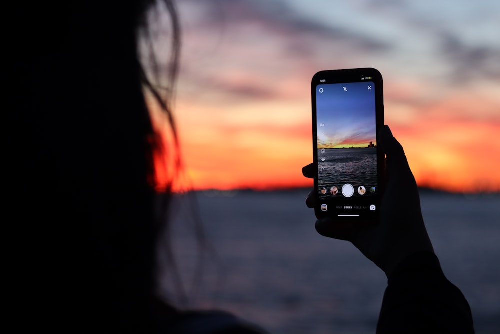 person holding black iphone 5 taking photo of sunset