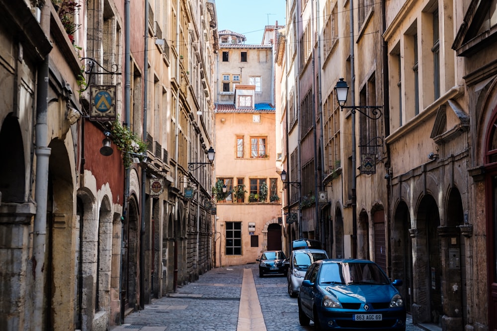 cars parked on side of the road in between buildings during daytime