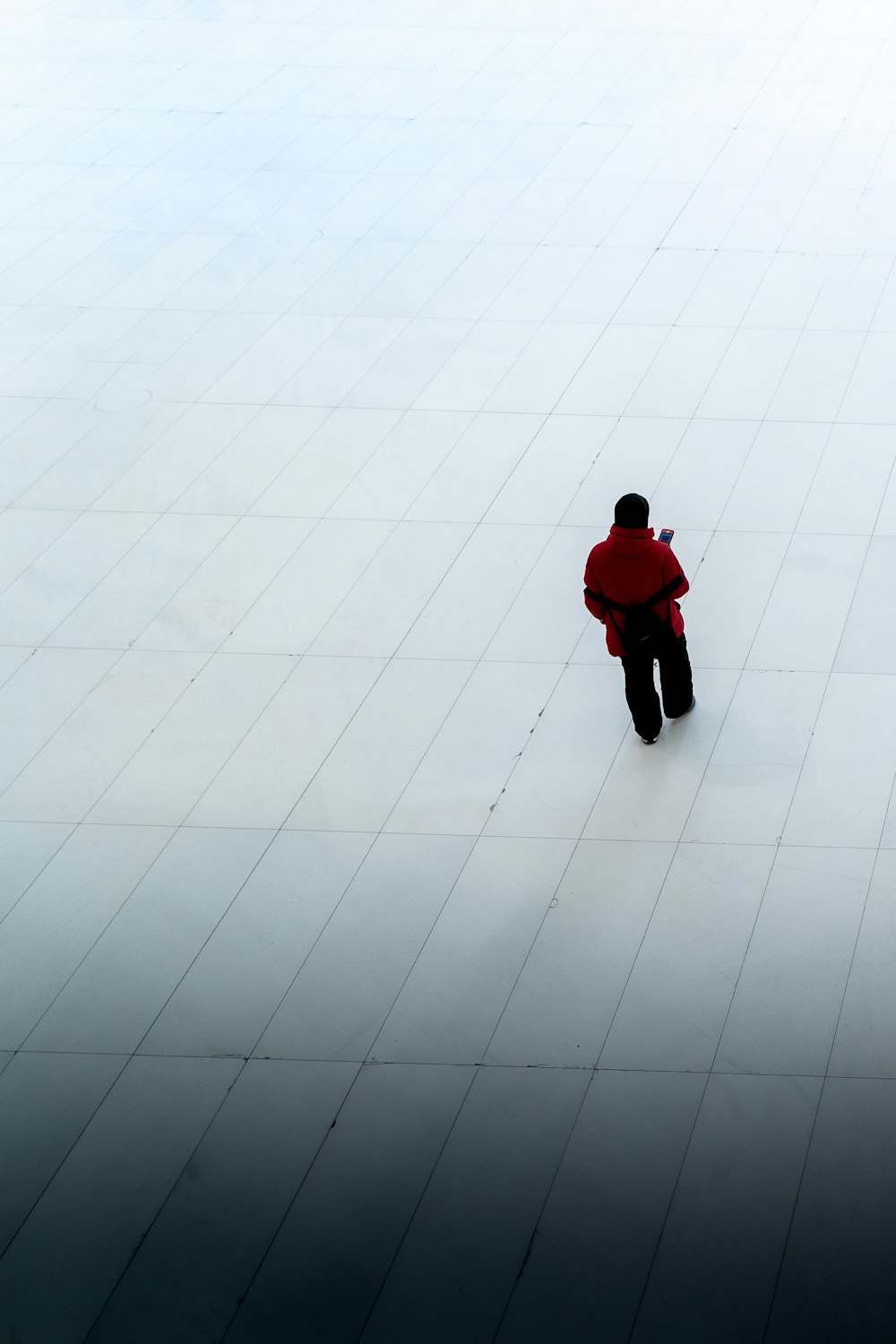 person in red hoodie and black pants walking on white floor