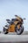 orange and black sports bike parked on gray concrete pavement during daytime