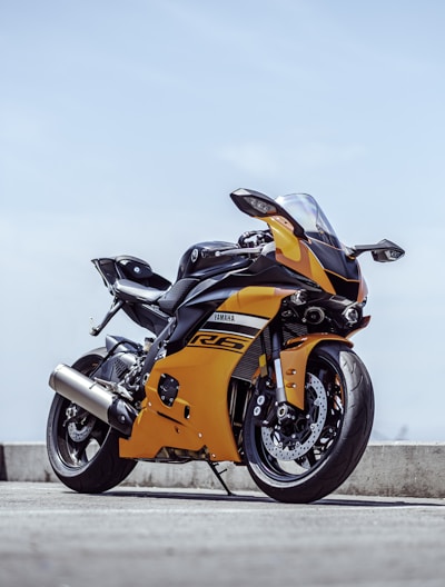 orange and black sports bike parked on gray concrete pavement during daytime