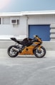 orange and black sports bike parked beside blue and white building