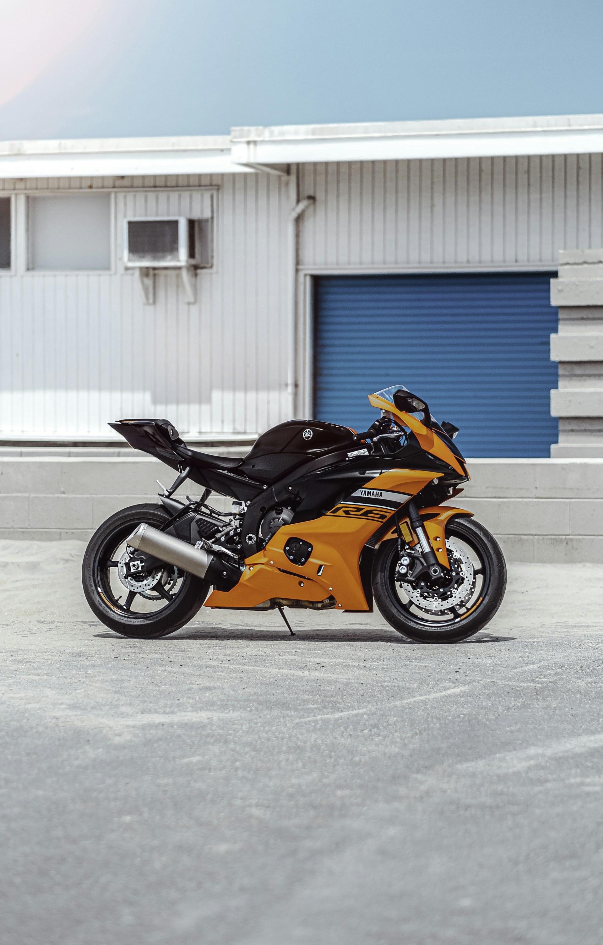 orange and black sports bike parked beside blue and white building