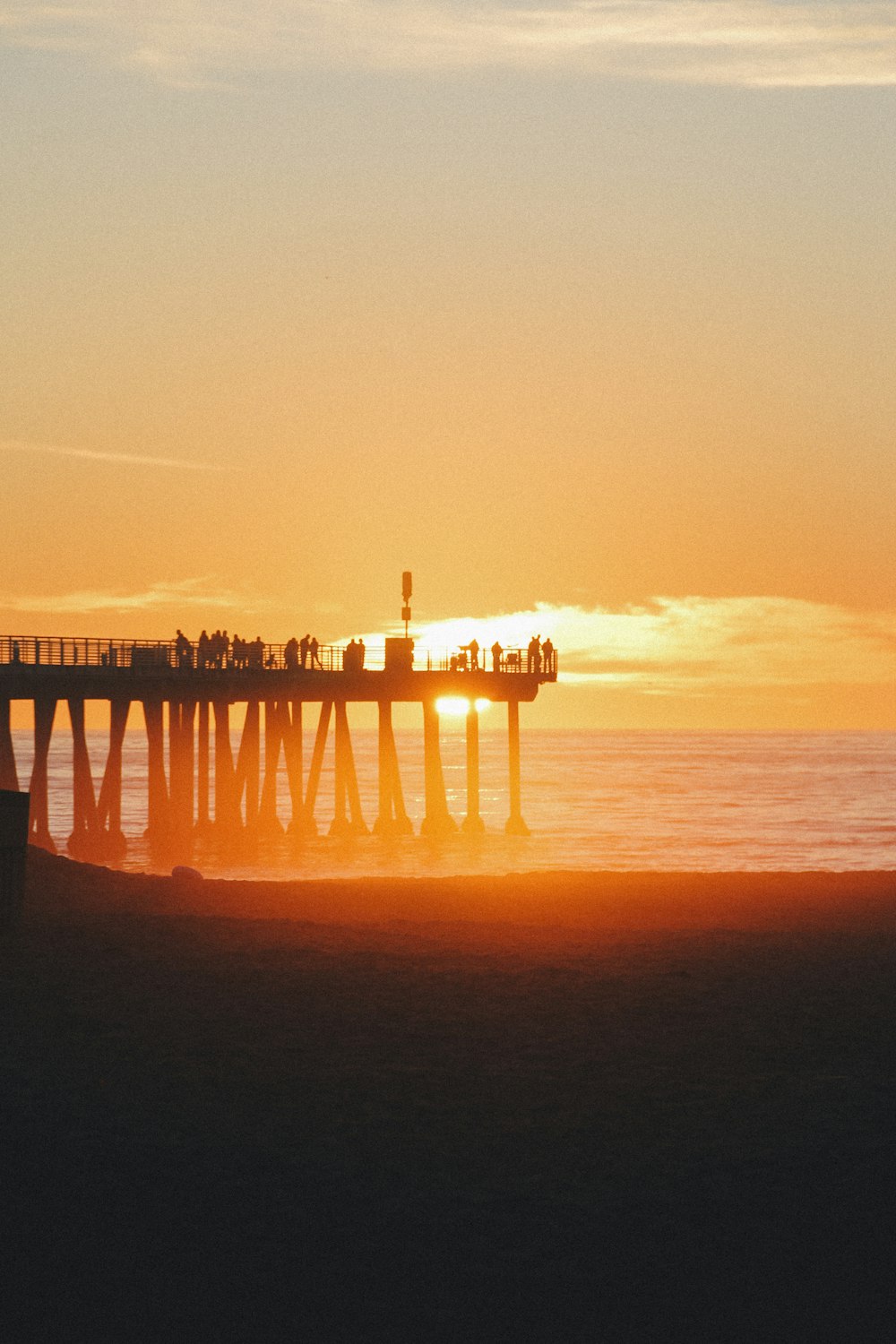 silhouette of dock on body of water during sunset