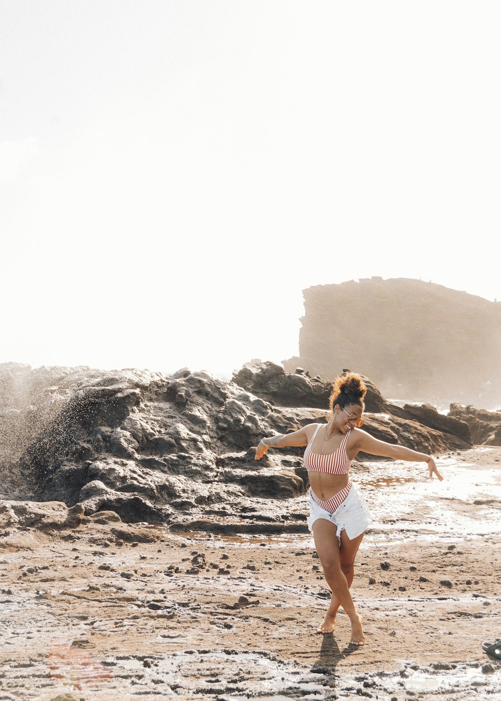 femme en bikini blanc debout sur le sable brun pendant la journée