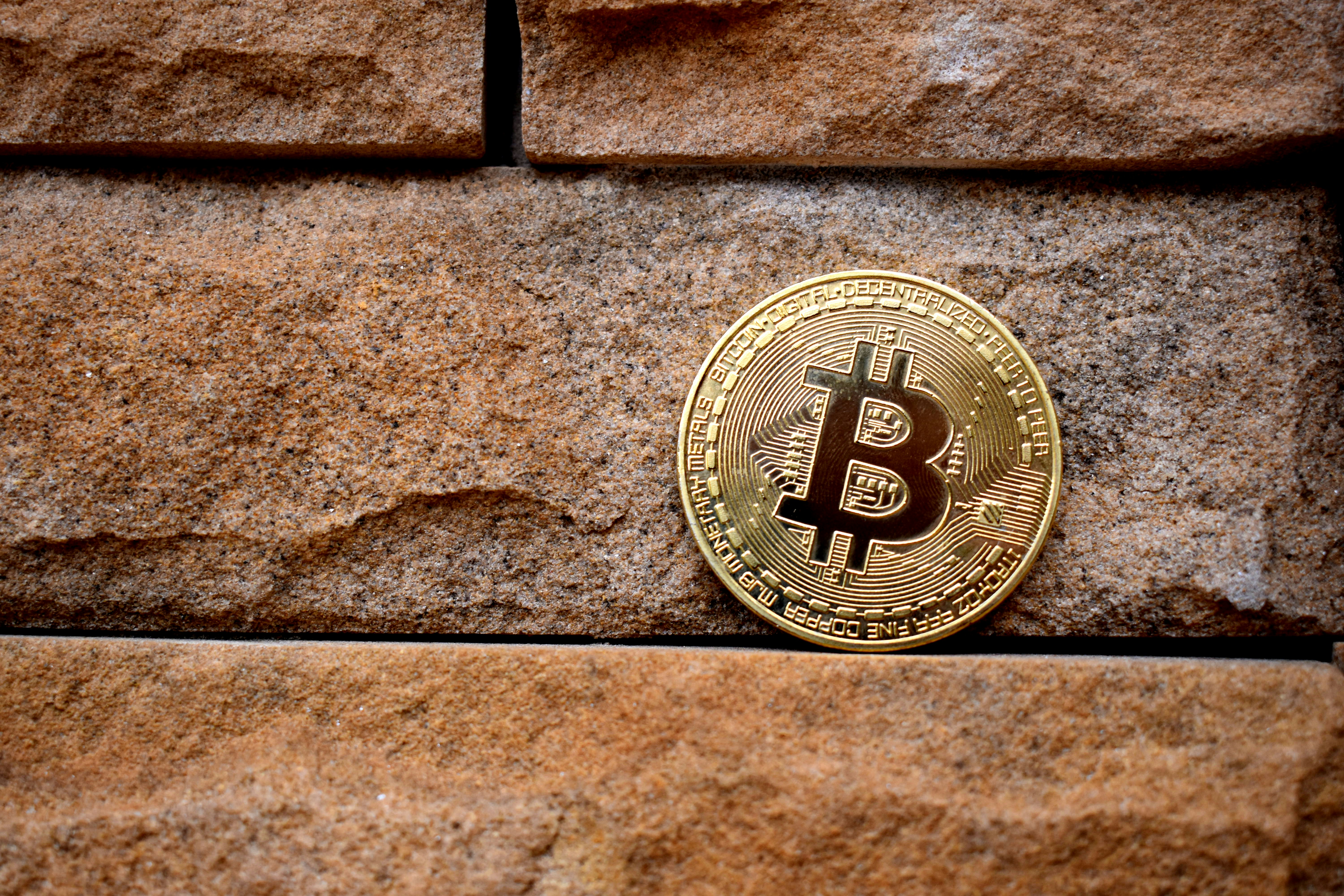 A Bitcoin on the cracks and crevices of a brick wall.