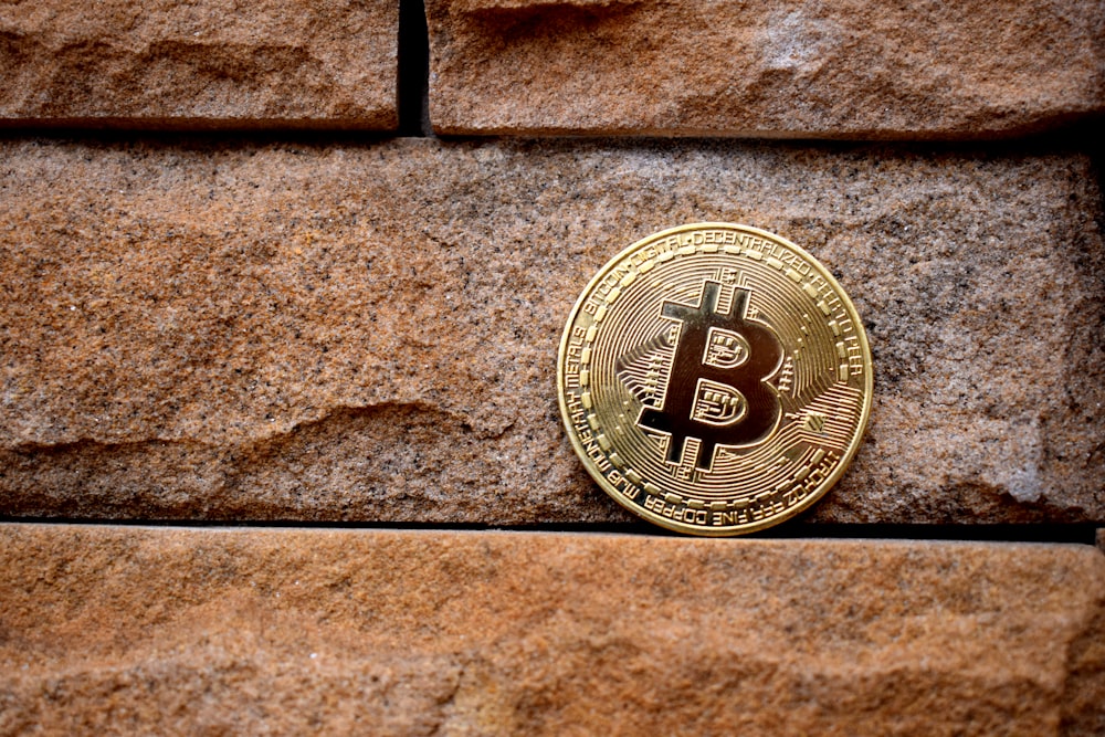 gold round coin on brown brick wall