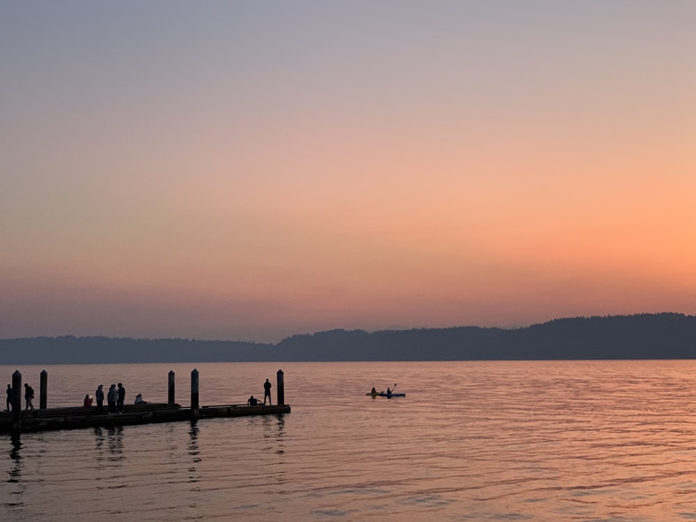 silhouette of people on sea during sunset