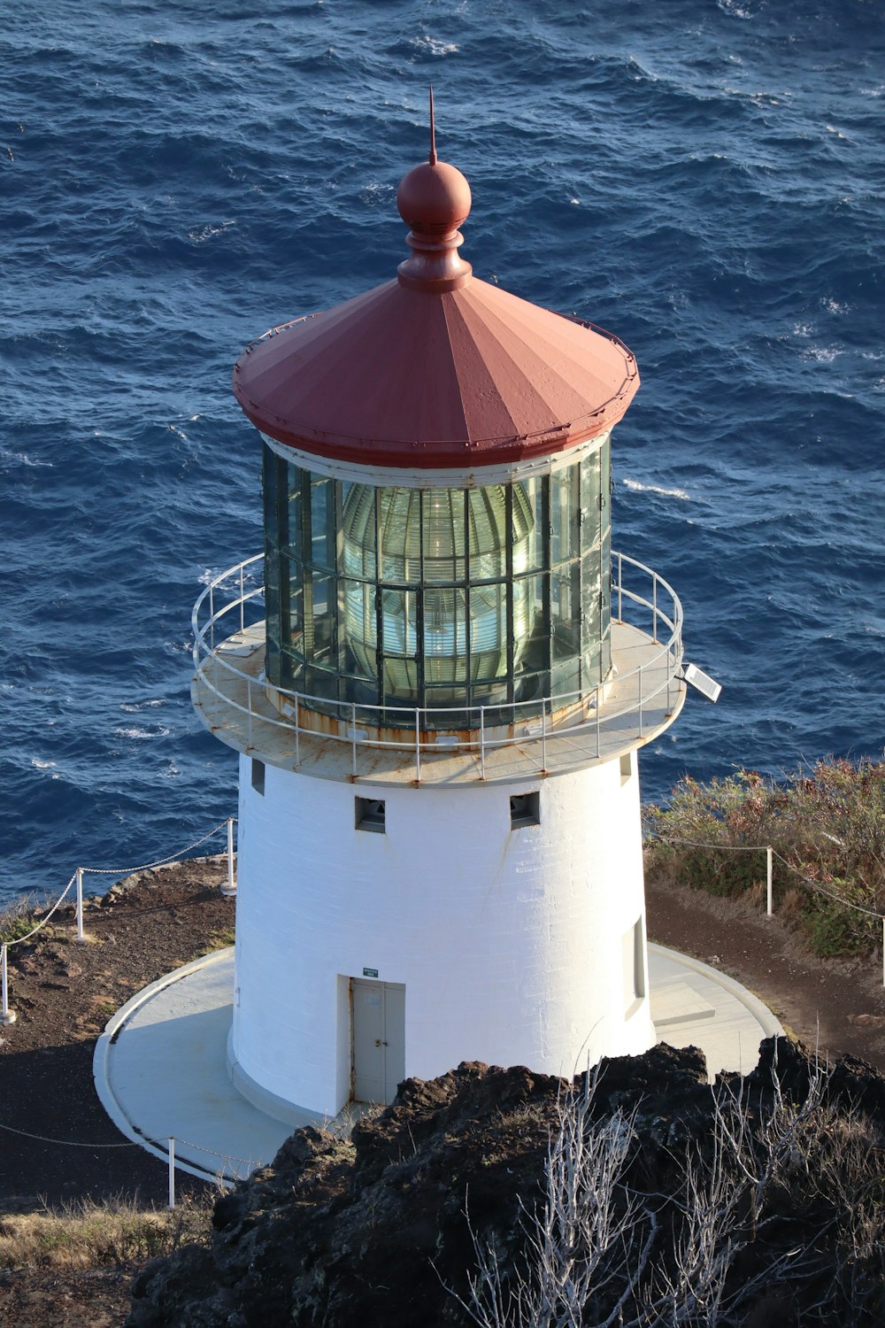 Faro bianco e rosso vicino allo specchio d'acqua durante il giorno