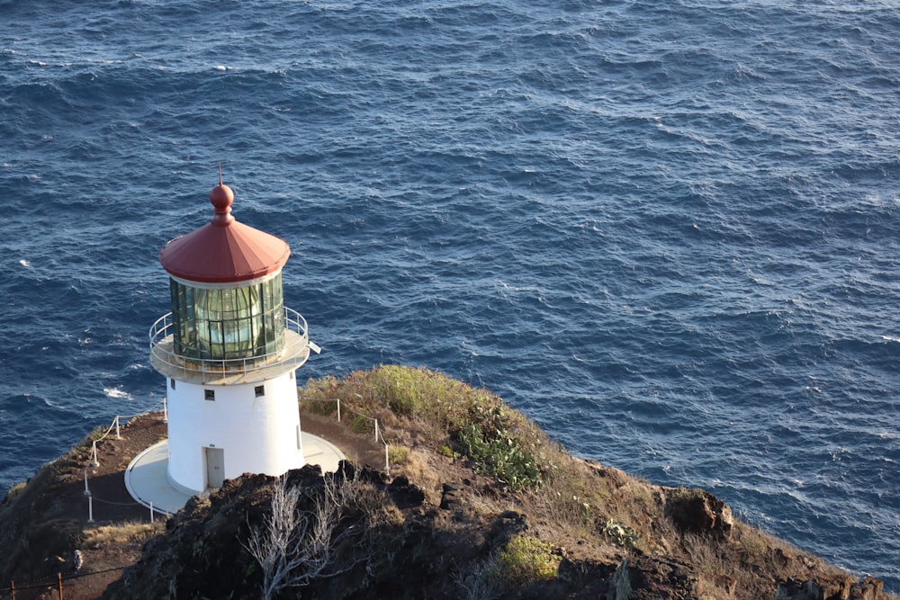 white and red lighthouse near body of water during daytime