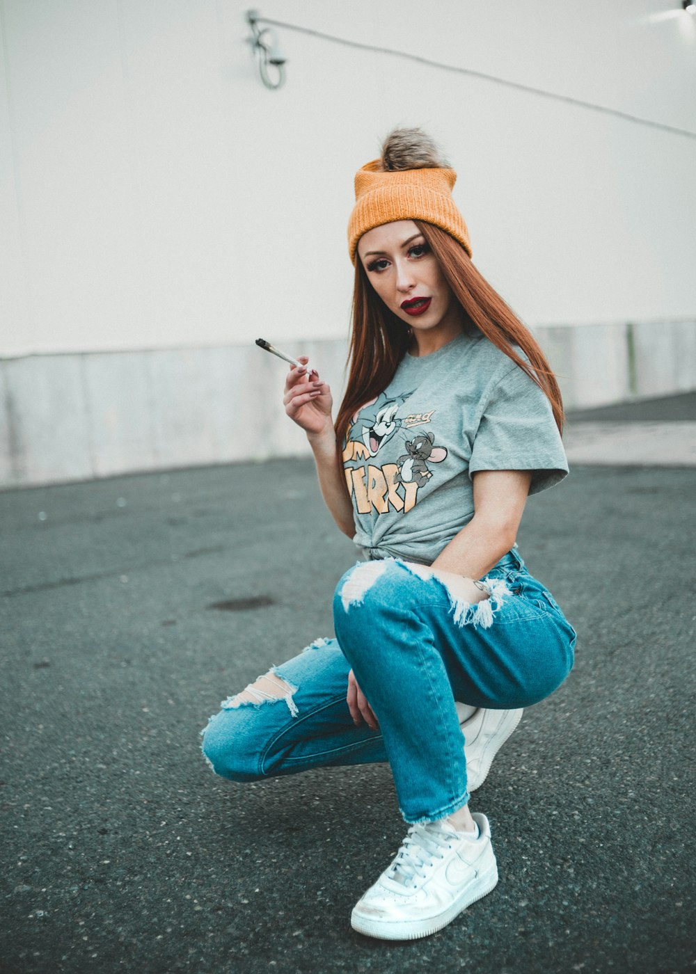 woman in gray t-shirt and blue denim jeans sitting on gray concrete floor
