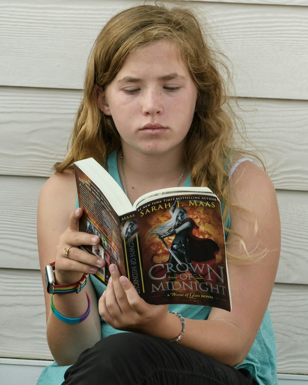 girl in blue tank top holding book