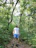 Man in casual attire enjoying a walk in a lush forest, with a confident expression.