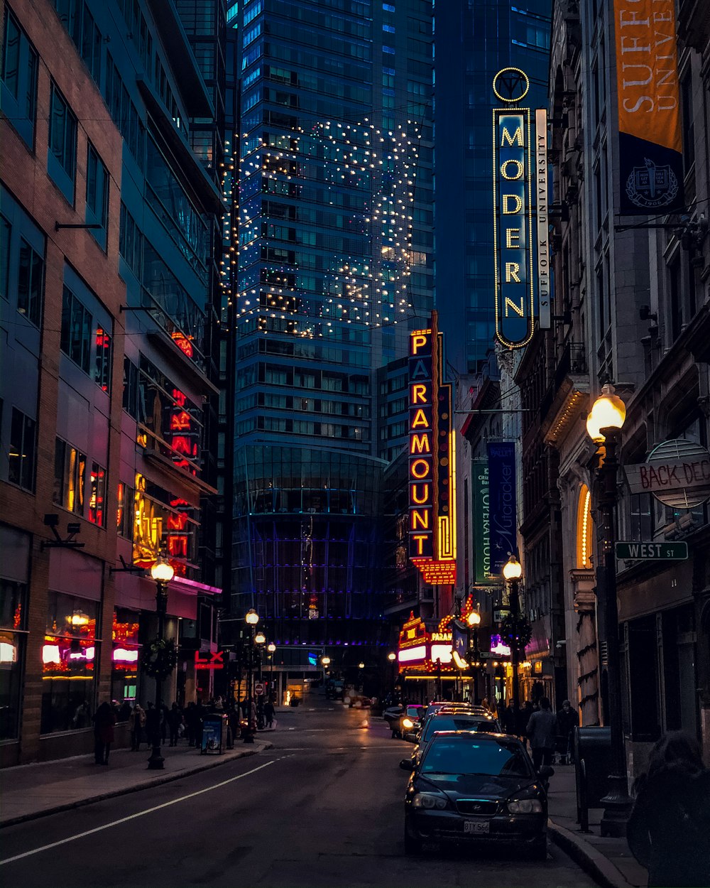 cars on road in between high rise buildings during night time