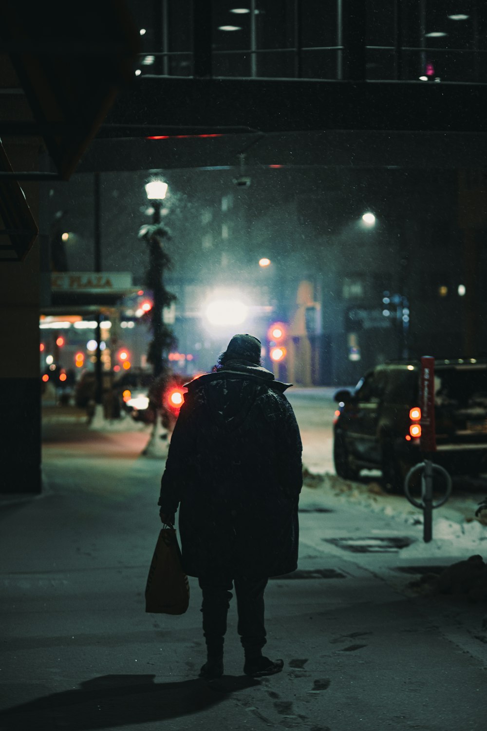 person in black coat walking on sidewalk during night time