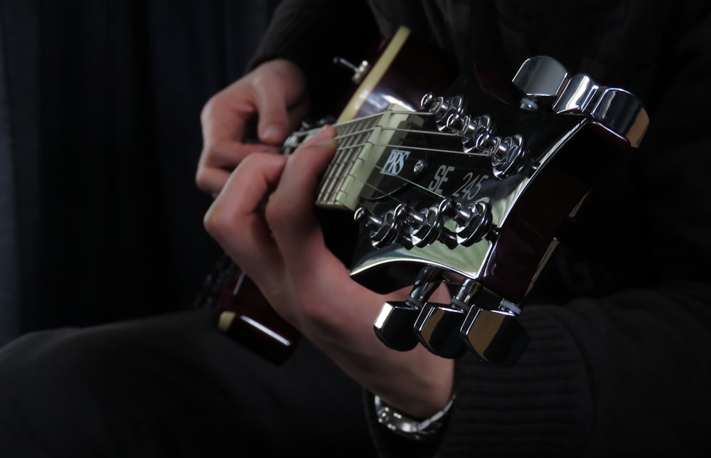 person playing black and white electric guitar