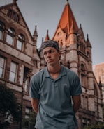 man in blue polo shirt standing near brown concrete building during daytime