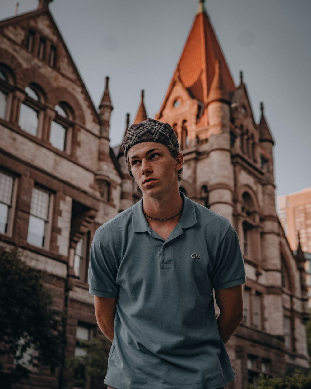 man in blue polo shirt standing near brown concrete building during daytime