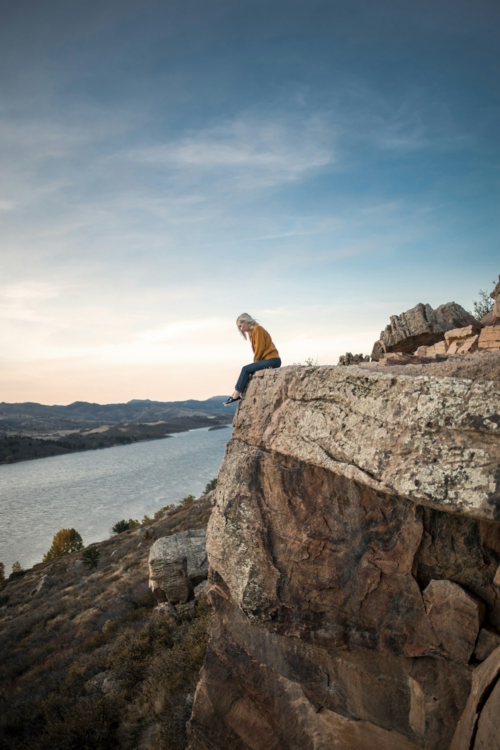 woman in blue jacket sitting on brown rock formation during daytime