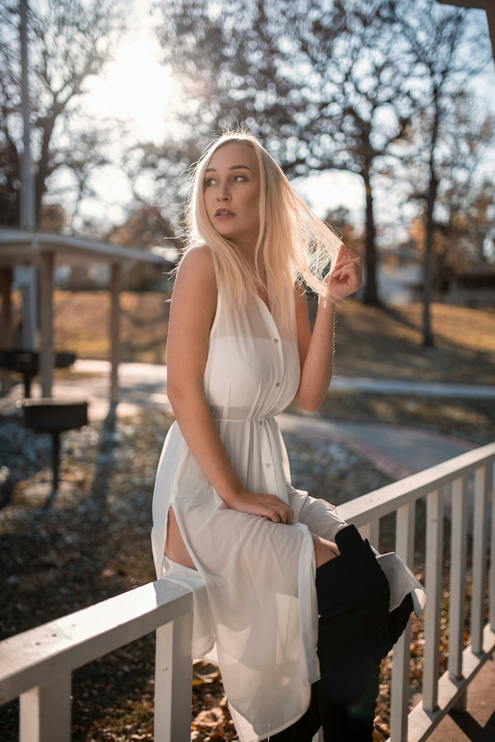 woman in white sleeveless dress sitting on white wooden bench during daytime