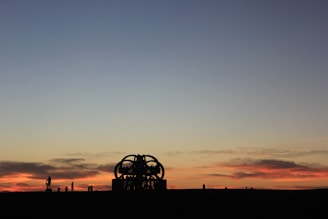 A sunset view of an outdoor art exhibit featuring sculptures and paintings from African diaspora artists.