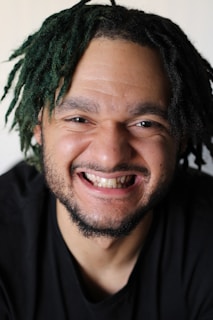 A young person proudly showing off their finished dreadlocks, beaming with confidence and accomplishment