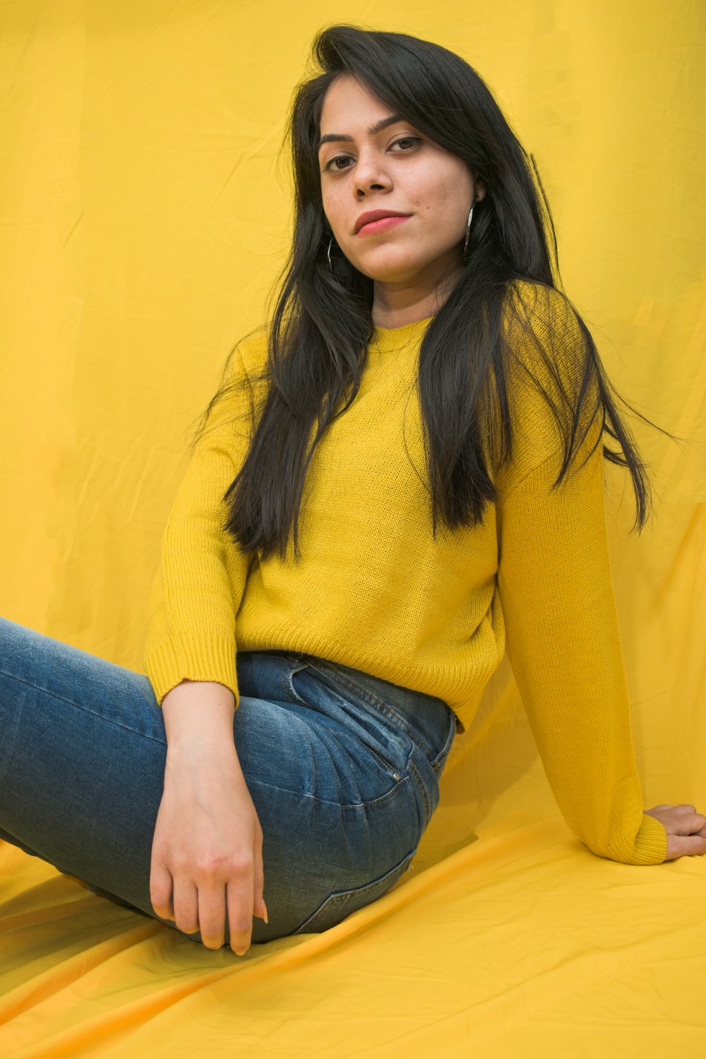 woman in yellow sweater and blue denim jeans sitting on yellow sofa