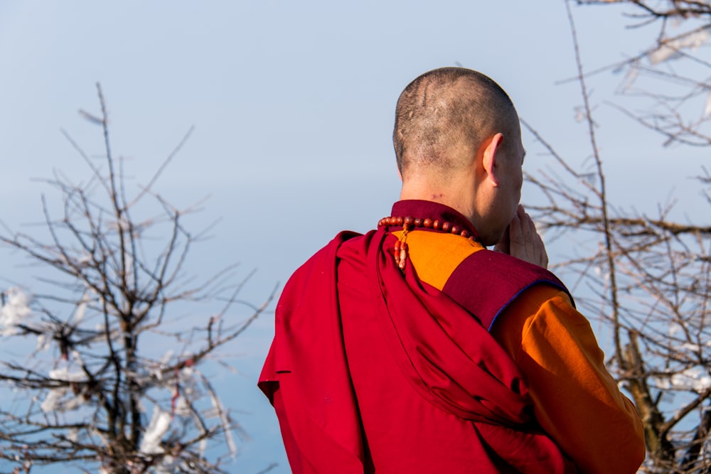 man in red jacket standing near bare tree during daytime