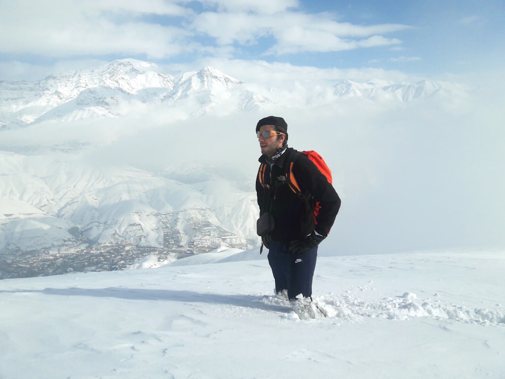 hombre con chaqueta negra y roja de pie en el suelo cubierto de nieve