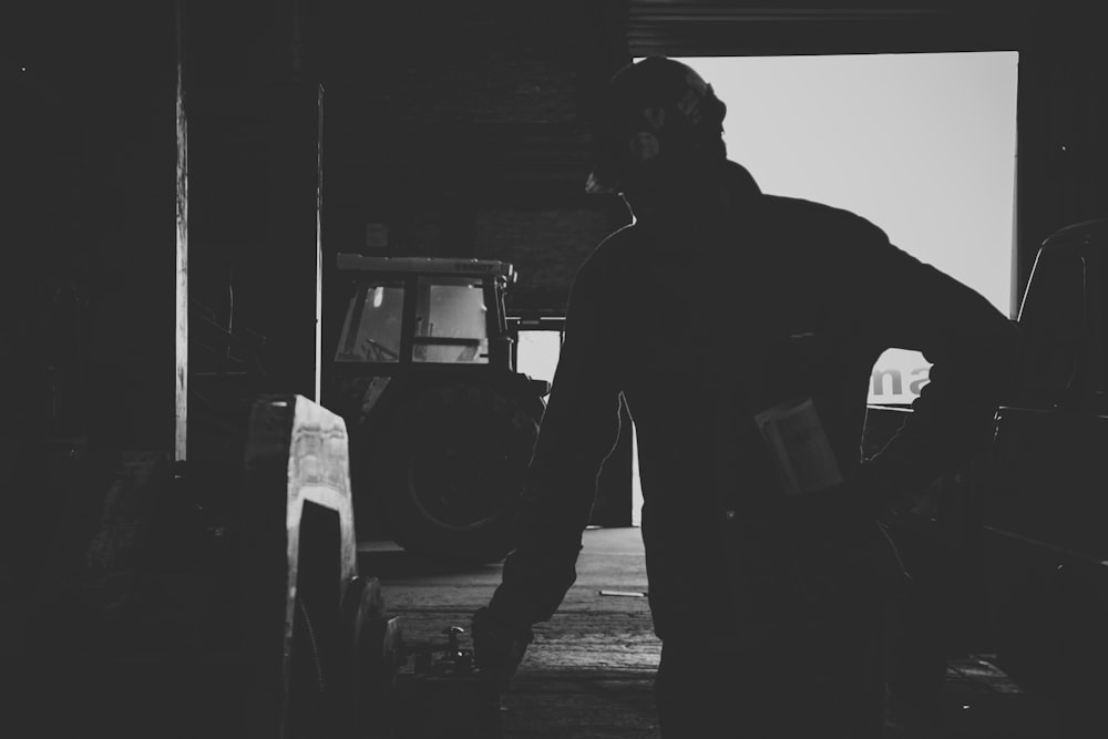 man in black tank top standing near car in grayscale photography