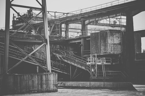 An industrial structure with metal beams and concrete elements, featuring a complex network of platforms and staircases. The scene has a rugged and utilitarian architecture.