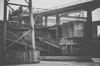 An industrial structure with metal beams and concrete elements, featuring a complex network of platforms and staircases. The scene has a rugged and utilitarian architecture.