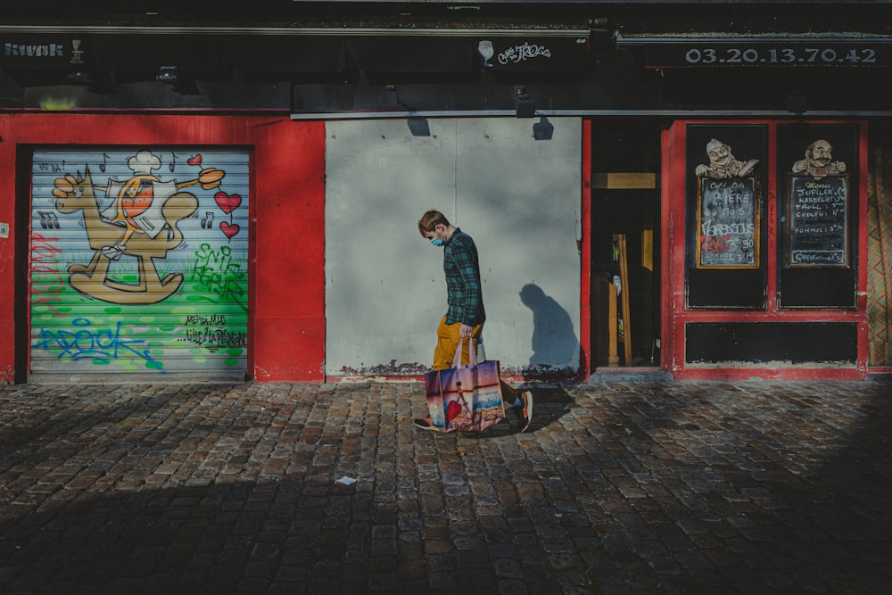 man in black jacket standing beside red and white wall