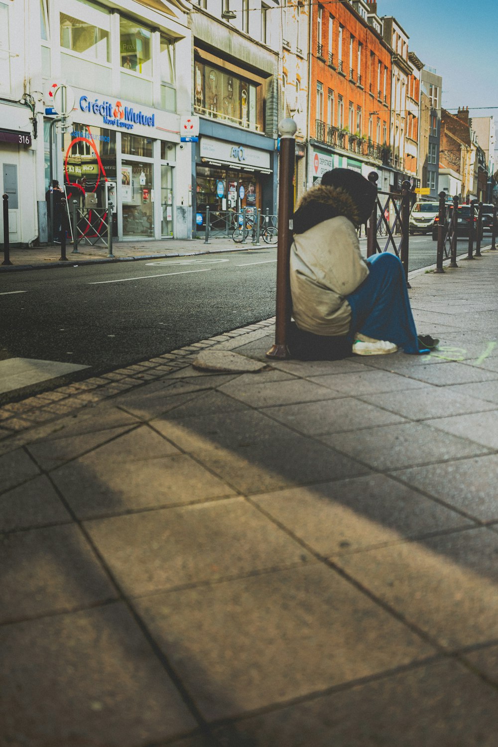 woman in white shirt sitting on sidewalk during daytime