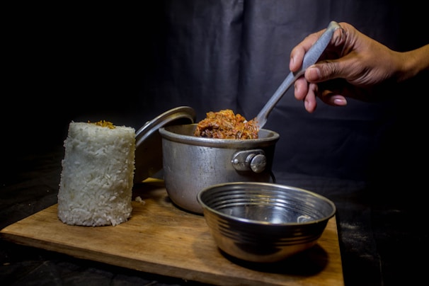 Hand holding a spoonful of rich, aromatic bumbu paste over a pot.