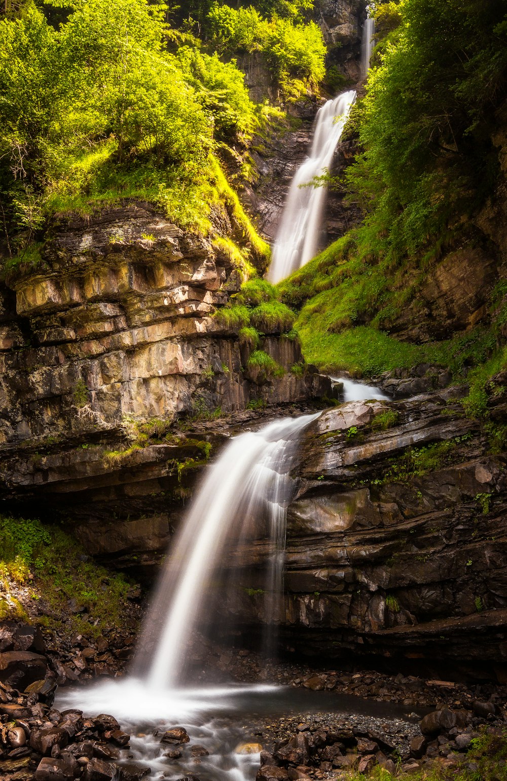 waterfalls between brown rocky mountain during daytime