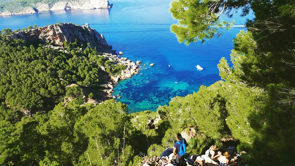 people on a cliff by a lake