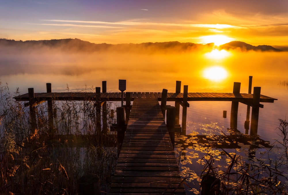 brown wooden dock on body of water during sunset