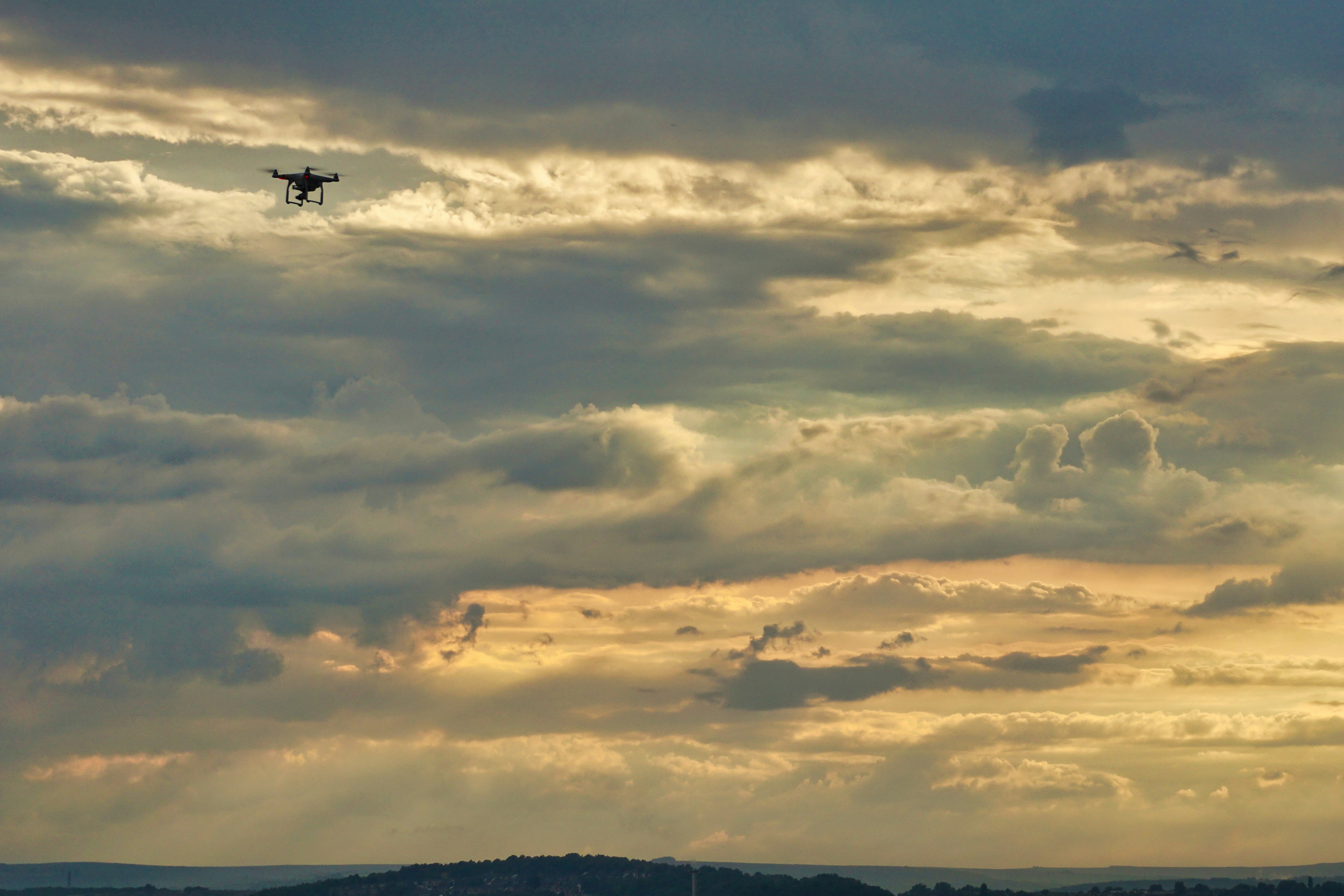 Aerial drone shot being prepared by crew members on a dramatic outdoor location at golden hour